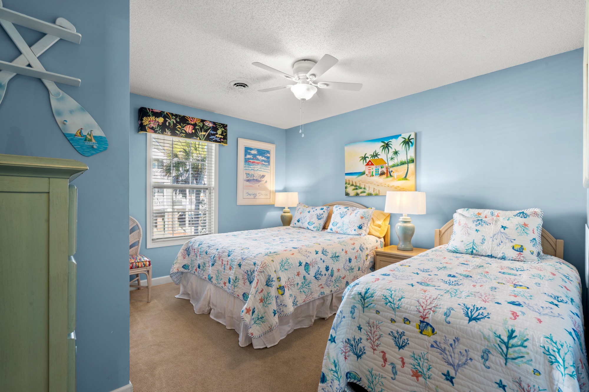 Bedroom four with blue walls, coral quilts, and beach artwork