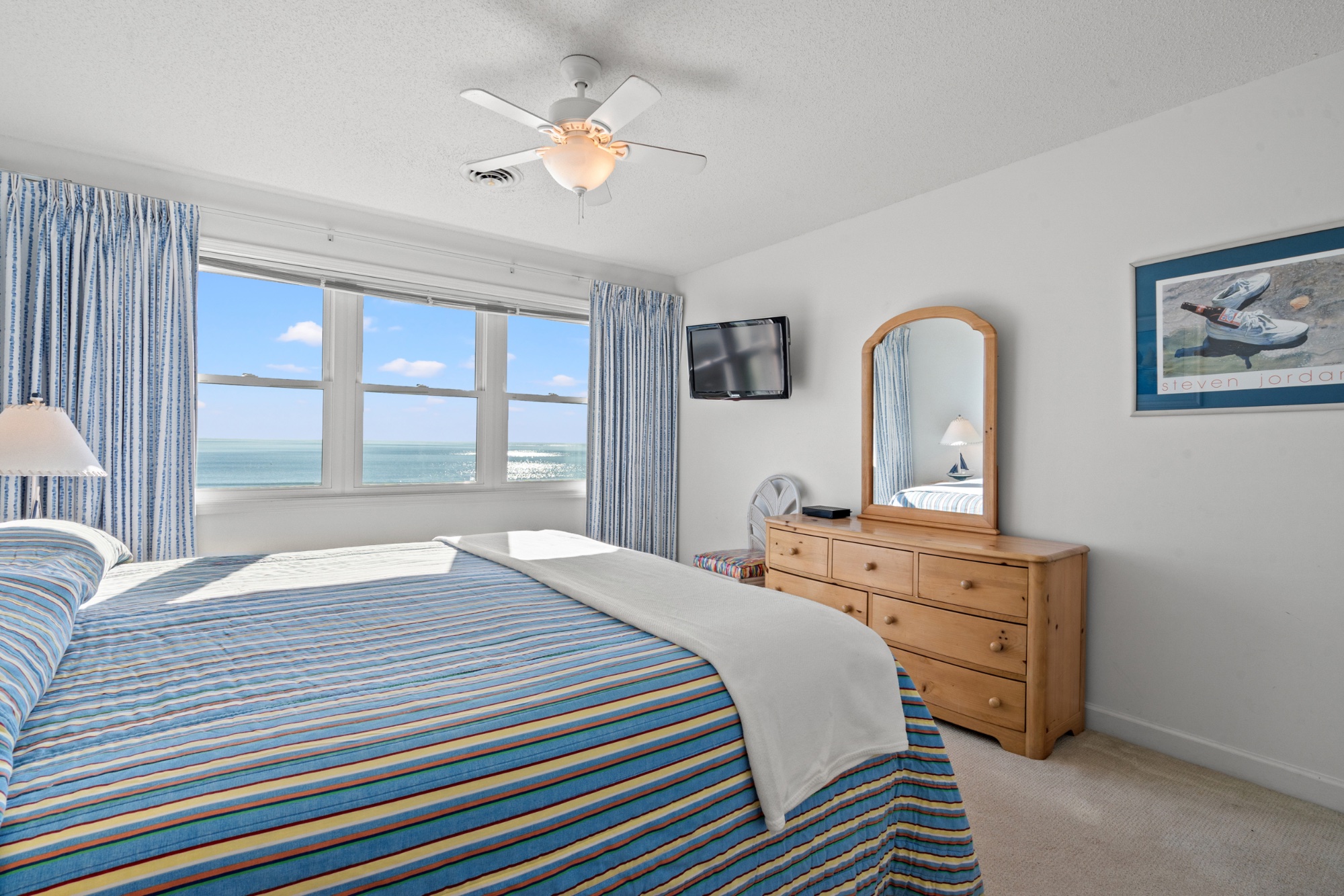 Guest king bedroom with striped bedspread and ocean view